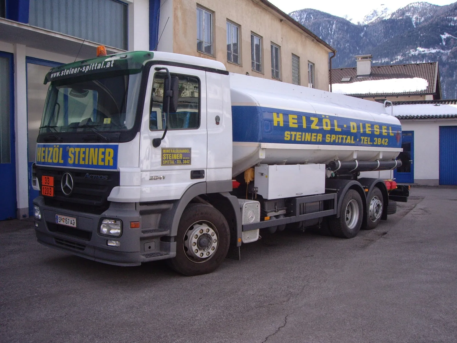 Tankwagen Heizöl Steiner im Hof, dahinter verschneite Berge
